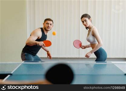 Friends playing sport game, group ping pong indoors. People in sportswear holds rackets and plays table tennis in gym. Friends playing sport game, group ping pong