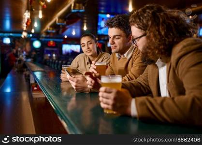 Friends rest in sport bar on Friday weekend. Focus on young man drinking cool beer. Leisure activity, friendship. Friends rest in sport bar, focus on young man drinking beer