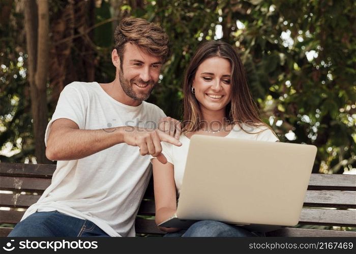 friends sitting bench with laptop