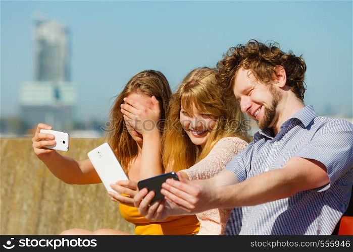 Friends taking selfie self photo picture with smartphone. Young women and man having fun outdoor. Summer relax.