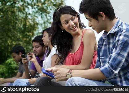 Friends using cell phone with people in the background