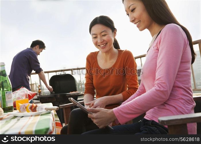 Friends Using Digital Tablet at Rooftop Barbecue