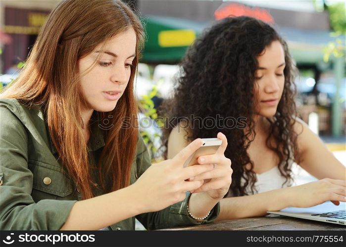 Friends using smartphone and laptop at coffee shop. Communication concept.