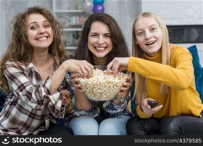 friends watching film while eating popcorn