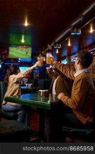 Friends watching football match translation clinking beer mug. Excited diverse hopeful fans rest in sport bar. Friends watching football match clinking beer mug rest in sport bar