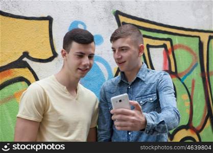 Friends watching the phone in the street with a painted wall graffiti background