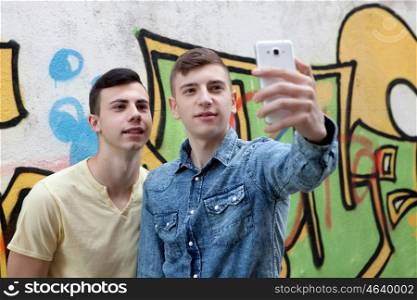 Friends watching the phone in the street with a painted wall graffiti background