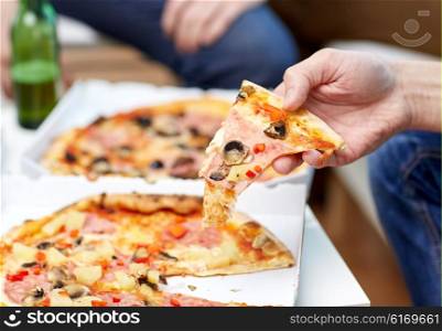 friendship, alcohol, people, celebration and holidays concept - close up of male friends drinking beer and eating pizza at home