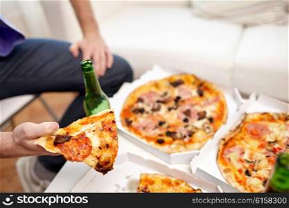 friendship, alcohol, people, celebration and holidays concept - close up of man drinking beer and eating pizza at home
