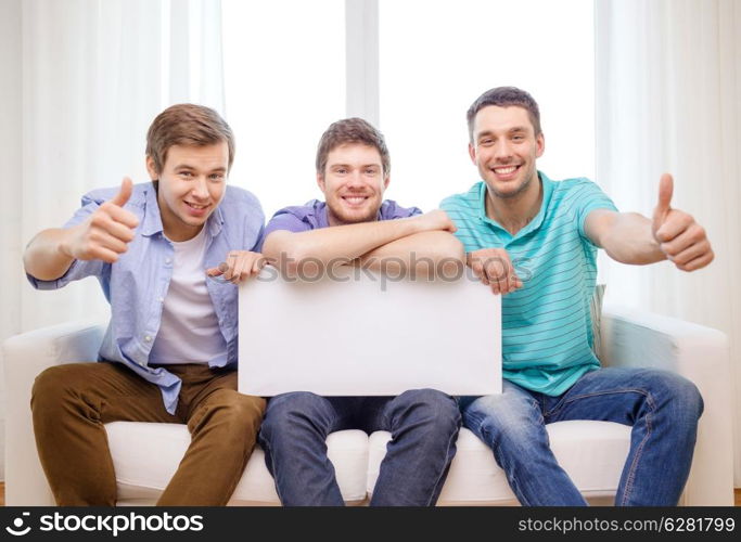 friendship and advertising concept - smiling male friends holding white blank board and showing thumbs up