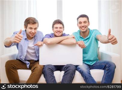 friendship and advertising concept - smiling male friends holding white blank board and showing thumbs up
