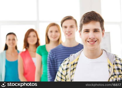 friendship and education concept - smiling male student in front of group of classmates