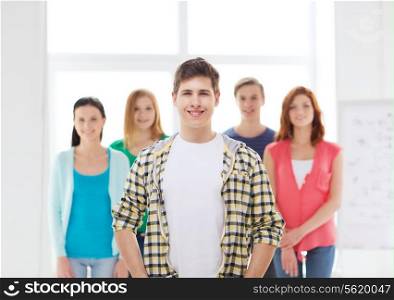 friendship and education concept - smiling male student in front of group of classmates