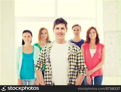 friendship and education concept - smiling male student in front of group of classmates