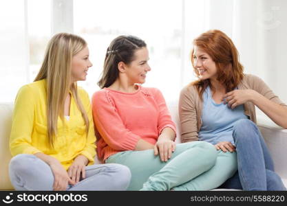 friendship and happiness concept - three girlfriends having a talk at home