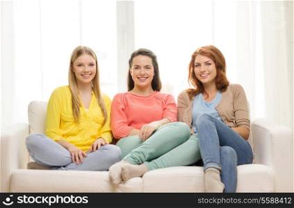 friendship and happiness concept - three girlfriends having a talk at home