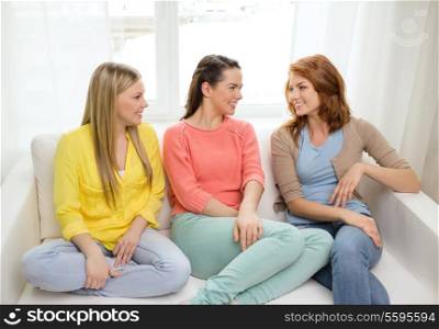 friendship and happiness concept - three girlfriends having a talk at home