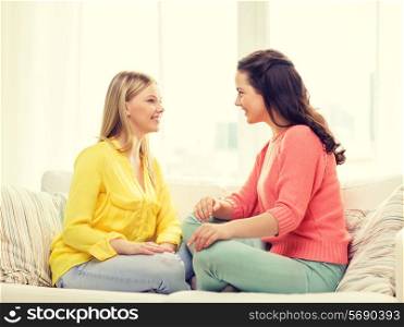friendship and happiness concept - two girlfriends having a talk at home