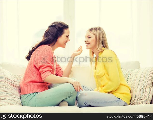 friendship and happiness concept - two girlfriends having a talk at home