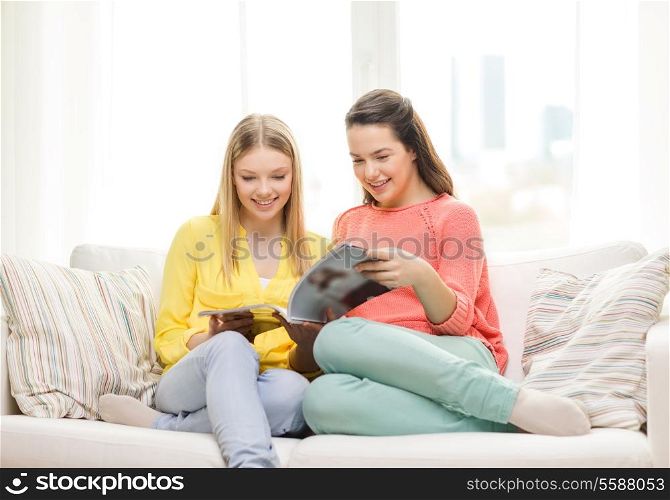 friendship and happiness concept - two girlfriends reading magazine at home