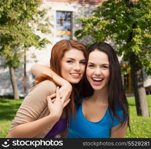 friendship and happy people concept - two laughing girls hugging