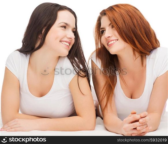 friendship and happy people concept - two laughing girls in white t-shirt looking at each other. two laughing girls in white t-shirts