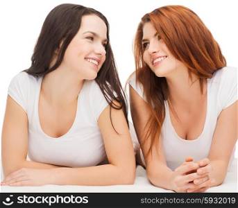 friendship and happy people concept - two laughing girls in white t-shirt looking at each other. two laughing girls in white t-shirts