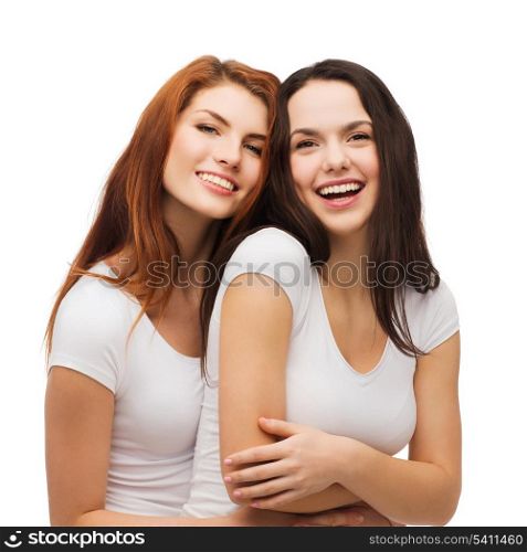 friendship and happy people concept - two laughing girls in white t-shirt hugging
