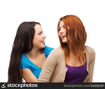 friendship and happy people concept - two laughing girls looking at each other