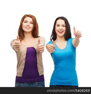 friendship and happy people concept - two smiling girls showing thumbs up