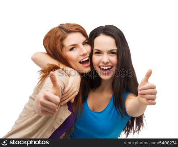 friendship and happy people concept - two smiling girls showing thumbs up