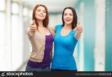friendship and happy people concept - two smiling girls showing thumbs up