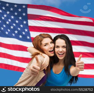 friendship and happy people concept - two smiling girls showing thumbs up over american flag background