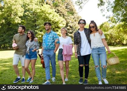 friendship and leisure concept - group of happy friends with guitar, picnic blanket and food at summer park. friends with guitar and picnic blanket at park