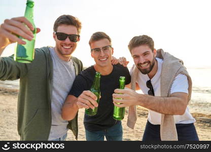 friendship and leisure concept - group of happy young men or male friends toasting non alcoholic beer on summer beach. young men toasting non alcoholic beer on beach