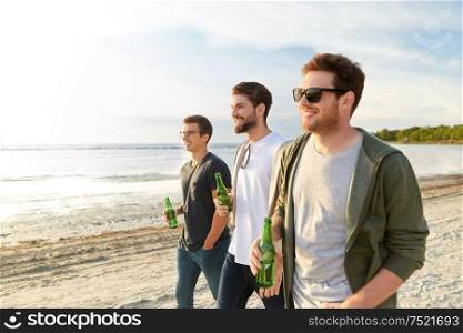 friendship and leisure concept - group of happy young men or male friends toasting non alcoholic beer walking along summer beach. young men with non alcoholic beer walking on beach
