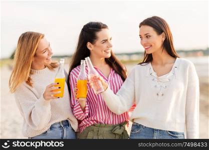 friendship and leisure concept - group of happy young women or female friends toasting non alcoholic drinks on summer beach. young women toasting non alcoholic drinks on beach