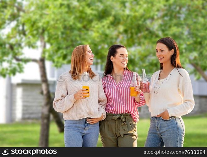 friendship and leisure concept - group of happy young women or female friends with non alcoholic drinks talking over summer garden background. young women with non alcoholic drinks talking