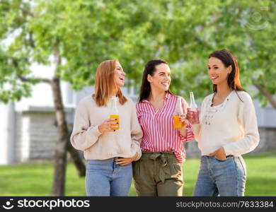 friendship and leisure concept - group of happy young women or female friends with non alcoholic drinks talking over summer garden background. young women with non alcoholic drinks talking