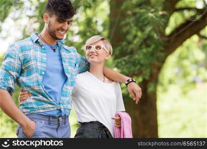 friendship and leisure concept - happy couple with picnic blanket at summer park. happy couple with picnic blanket at summer park