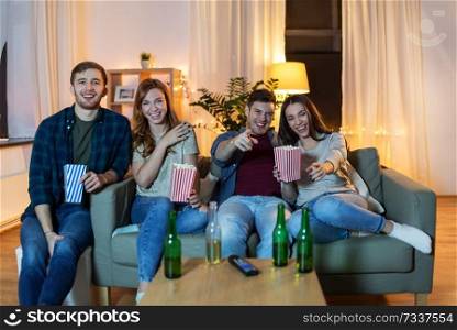 friendship and leisure concept - happy friends with non-alcoholic beer and popcorn watching comedy on tv at home in evening. friends with beer and popcorn watching tv at home