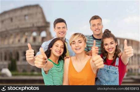 friendship and people concept - group of happy smiling friends showing thumbs up over coliseum background. happy friends showing thumbs up over coliseum