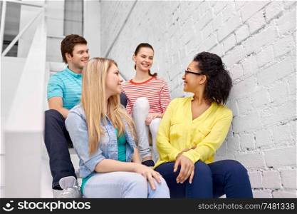 friendship and people concept - smiling teenage friends or students hanging out on stairs. teenage friends or students hanging out on stairs