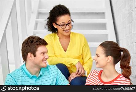 friendship and people concept - smiling teenage friends or students hanging out on stairs. teenage friends or students hanging out on stairs