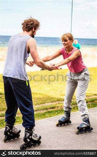 Friendship and spending time together. Outdoors activities sport and free time. Summertime exercising.. Young couple have fun together rollerblading in park learning.. Friends learn rollerblading together have fun at park.