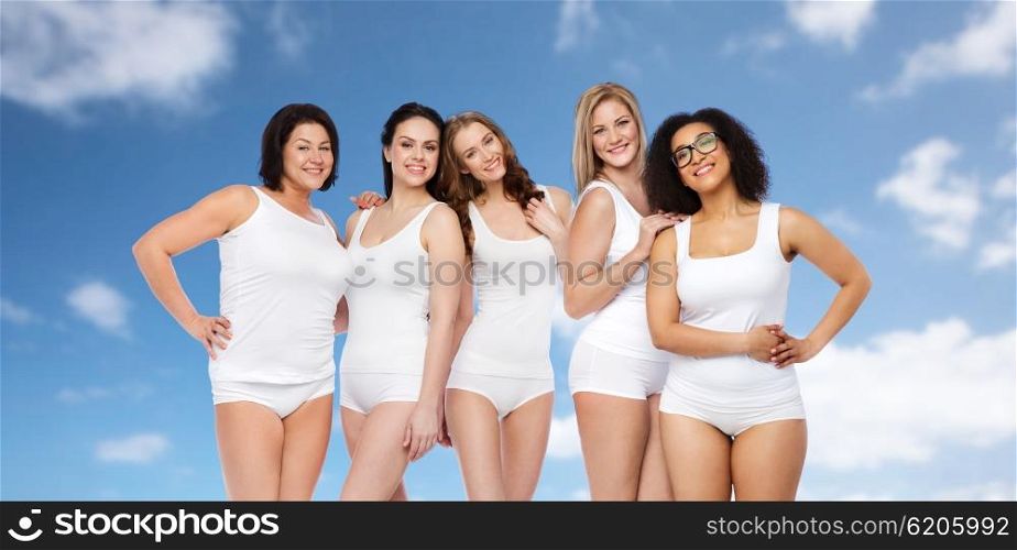 friendship, beauty, body positive and people concept - group of happy different size women in white underwear over blue sky and clouds background