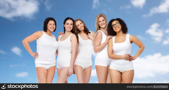 friendship, beauty, body positive and people concept - group of happy different size women in white underwear over blue sky and clouds background