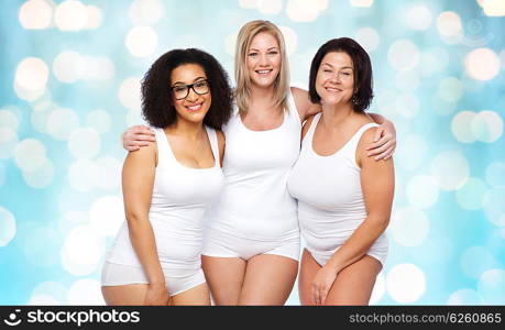 friendship, beauty, body positive and people concept - group of happy plus size women in white underwear over blue holidays lights background