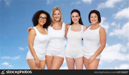 friendship, beauty, body positive and people concept - group of happy women different in white underwear over blue sky and clouds background