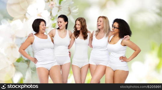 friendship, beauty, body positive and people concept - group of happy women different in white underwear over natural spring cherry blossom background